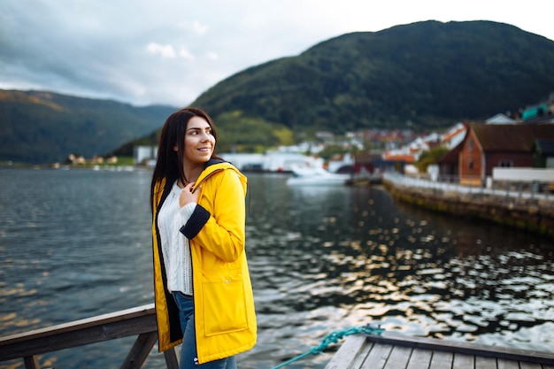 Photo girl tourist in yellow jacket posing on the lake in norway active woman relaxing in the norway