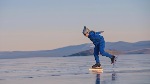 The girl train on ice speed skating. The child skates in the winter in blue sportswear suit, sport glasses. Children speed skating sport.