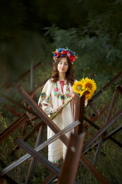 A girl in a Ukrainian national dress, against the background of anti-tank hedgehogs.war in Ukraine.