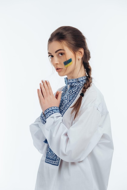 A girl in Ukrainian vyshyvanka holds a flag War in Ukraine on a white background