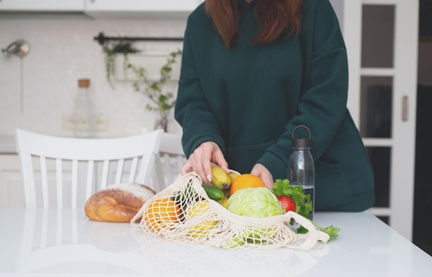 A girl unloads a bag of food on the kitchen table