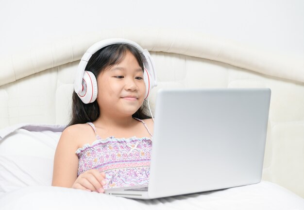 Girl using a laptop and listening to music at headphones