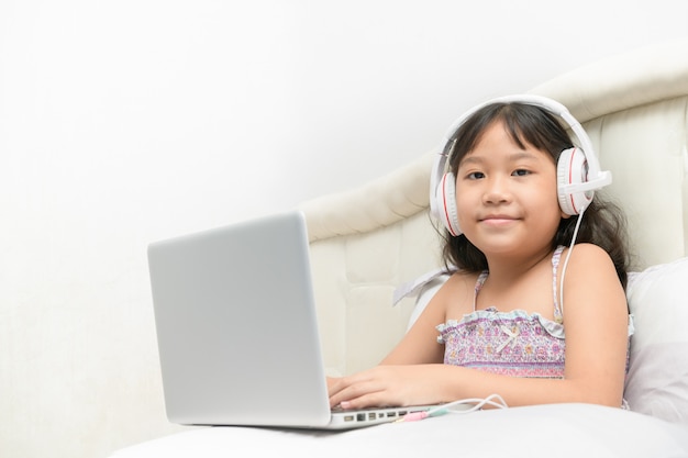 Girl using a laptop and listening to music at headphones