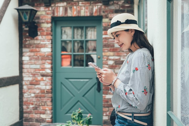 Girl using smart phone leaning against wall