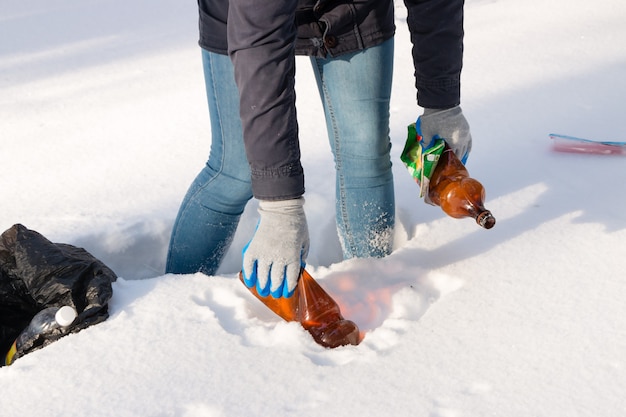 Girl volunteer collecting garbage in the winter