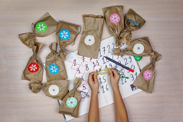 Photo girl waiting for christmas opening paper bag with sweets and crossing out date in calendar