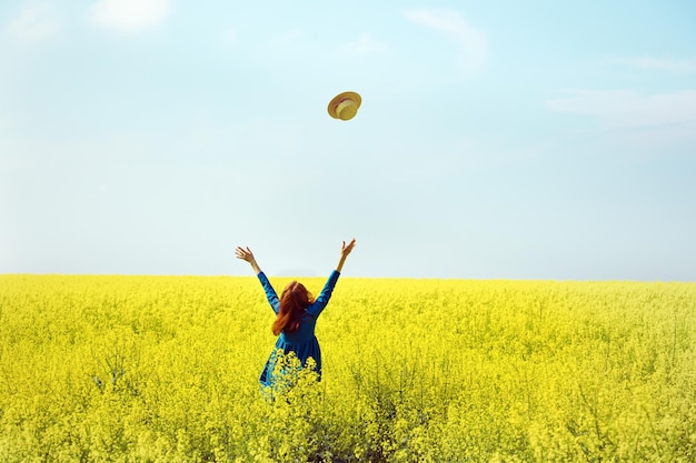 Girl walking in a field of yellow rapeseed