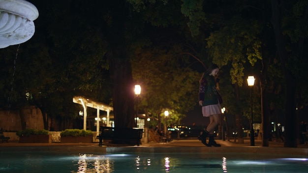 Girl walking fountain edge calm night woman relaxing at evening town square