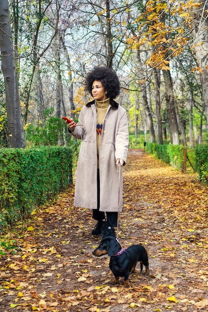 A girl walking with her dog in the park listening to music with headphones