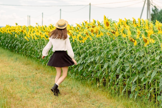 Girl walks across the field a glade of sunflowers happy girl is spinning airy skirt on a woman