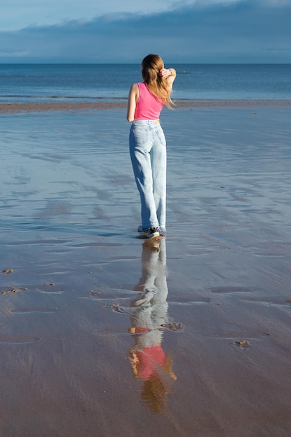 A girl walks along the coast of the North Sea in the UK