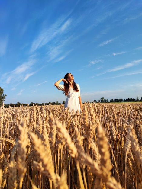 A girl walks gracefully between barley and wheat in Ukraine. Enjoys beauty of Ukrainian nature.