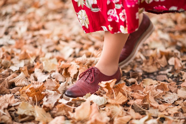 The girl walks in the park. Photo of female legs in maroon shoes