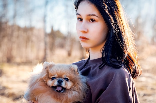 A girl walks with a dog in the park outdoor recreation with a pet a portrait with a small puppy