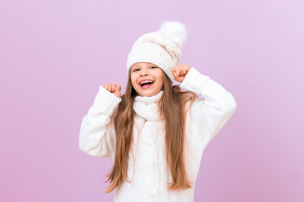 A girl in a warm winter sweater is very happy and smiles.