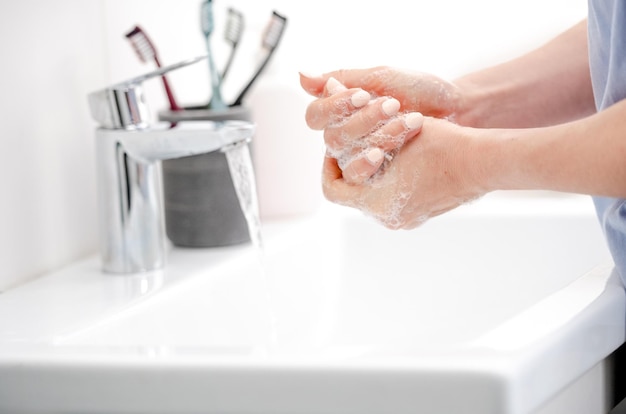 Girl washes hands with liquid soap in pristine bathtub