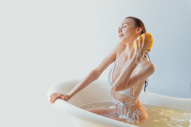 Girl washes her body with shower gel and shampoo with foam closeup