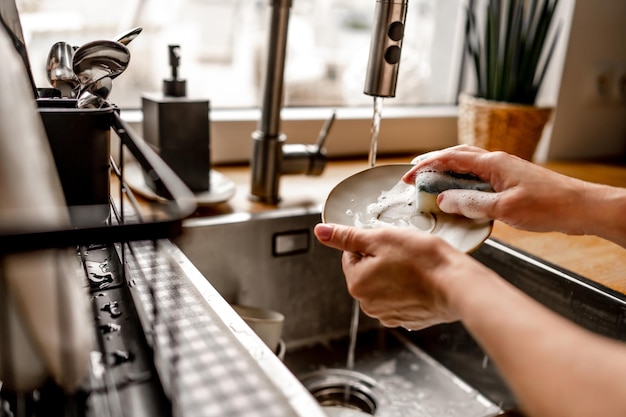 Girl washing dishes at kitchen at home