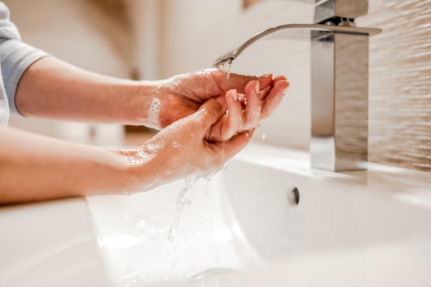 Girl washing hands with soap in bathroom