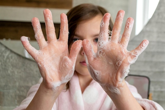 Girl washing hands with water and soap in bathroom