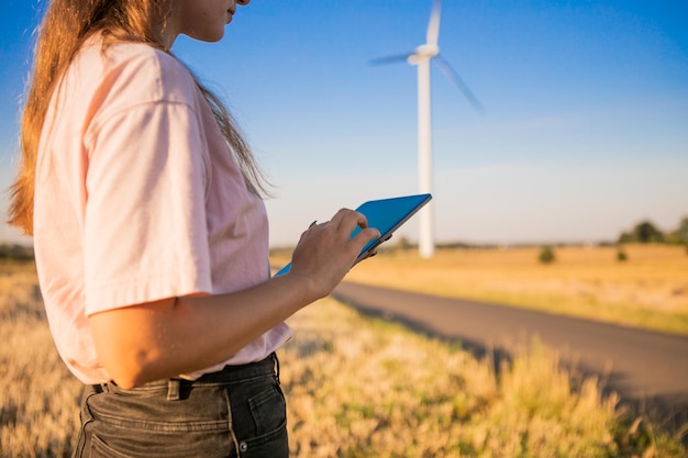 Girl watching windmills and watching at tablets