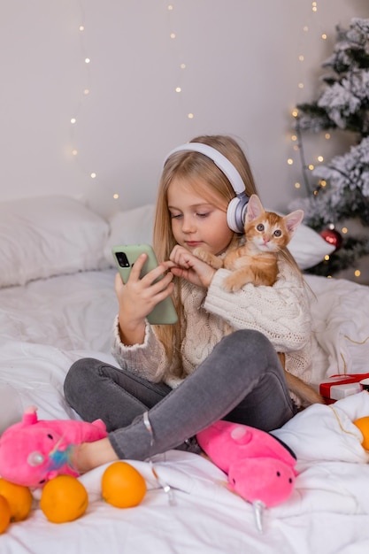 Girl wearing headphones and playing with a cat