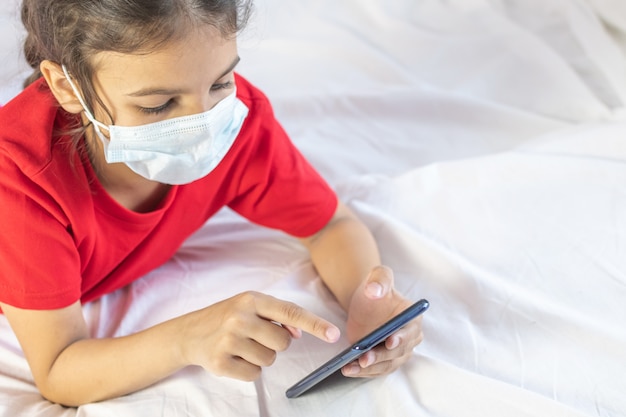 Girl wearing mask, using smartphone at home