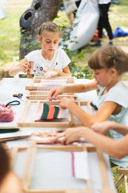 Photo girl weaving small rug with pattern at masterclass on weaving