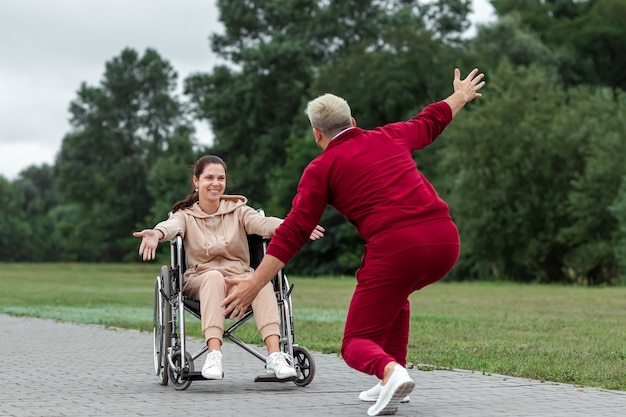 A girl on a wheelchair with a man spend time in the park. The young woman is disabled. The concept of a wheelchair, disabled person, full life, paralyzed, disabled person, health care.