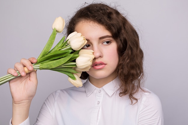 Girl in a white blouse holding a bouquet of yellow and white tulips