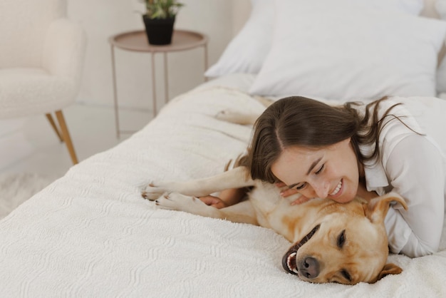 Girl in white clothes with dog labrador playing at home