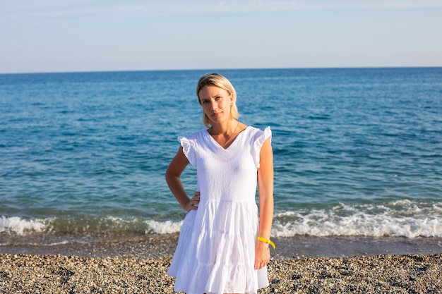 A girl on white dress walking by the sea