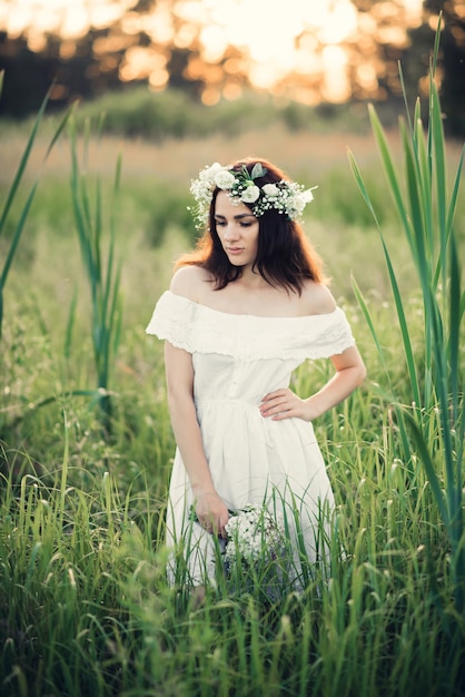 Girl in a white dress with a wreath and a bouquet of flowers