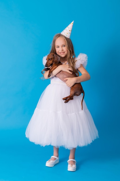 girl in a white fluffy elegant dress with a dachshund dog in her arms