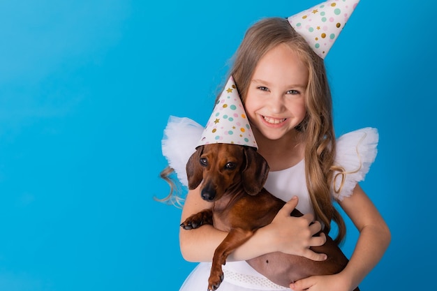 girl in a white fluffy elegant dress with a dachshund dog in her arms