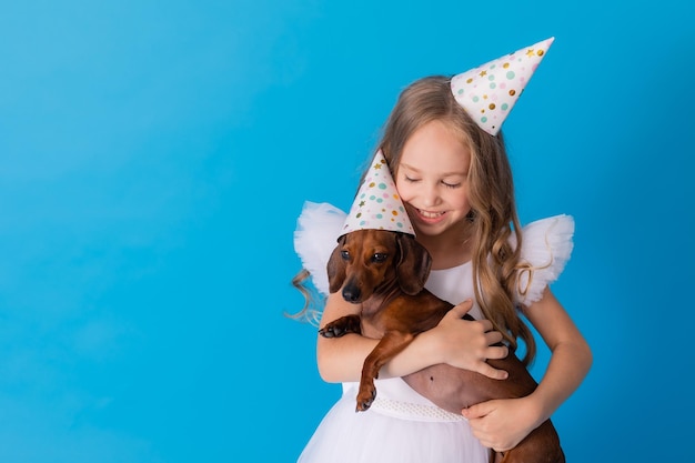 girl in a white fluffy elegant dress with a dachshund dog in her arms