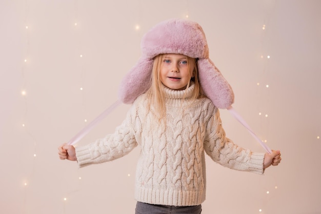 A girl in a white sweater and a pink hat