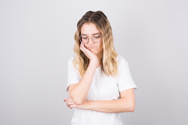 A girl in a white T-shirt looks down tired. The concept of fatigue, stress and overwork.