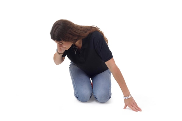 A girl who is on her knees on the floor looking for something to the side on a white background