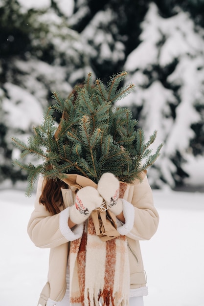 A girl in a winter forest with a bouquet of fir branches Snowy winter