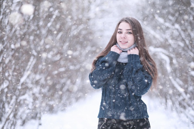 Girl in a winter park in the afternoon in snowfall