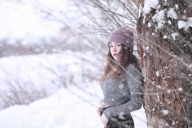 Girl in a winter park in the afternoon in snowfall