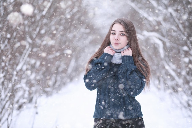 Girl in a winter park in the afternoon in snowfall