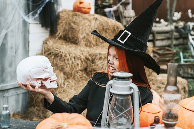 A girl in a witch costume having fun at a Halloween party on the decorated porch