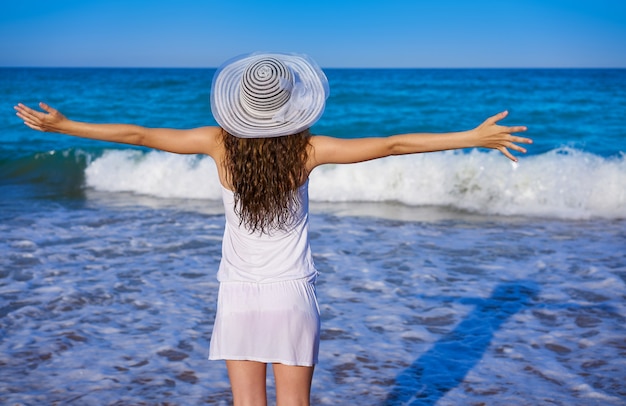 Girl with beach hat in sea open arms