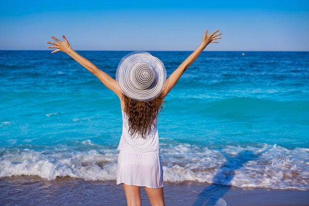 Girl with beach hat in sea open arms