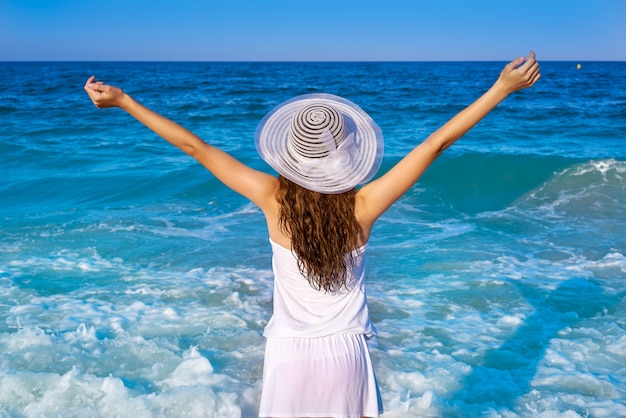 Girl with beach hat in sea open arms