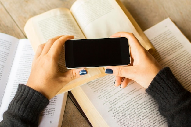 Girl with blank cell phone and books