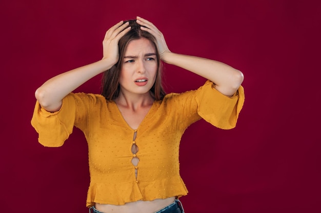 Girl with blond hair in a yellow blouse with a hand on her head