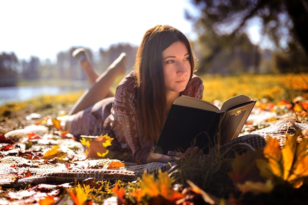 Girl with a book in autumn foliage